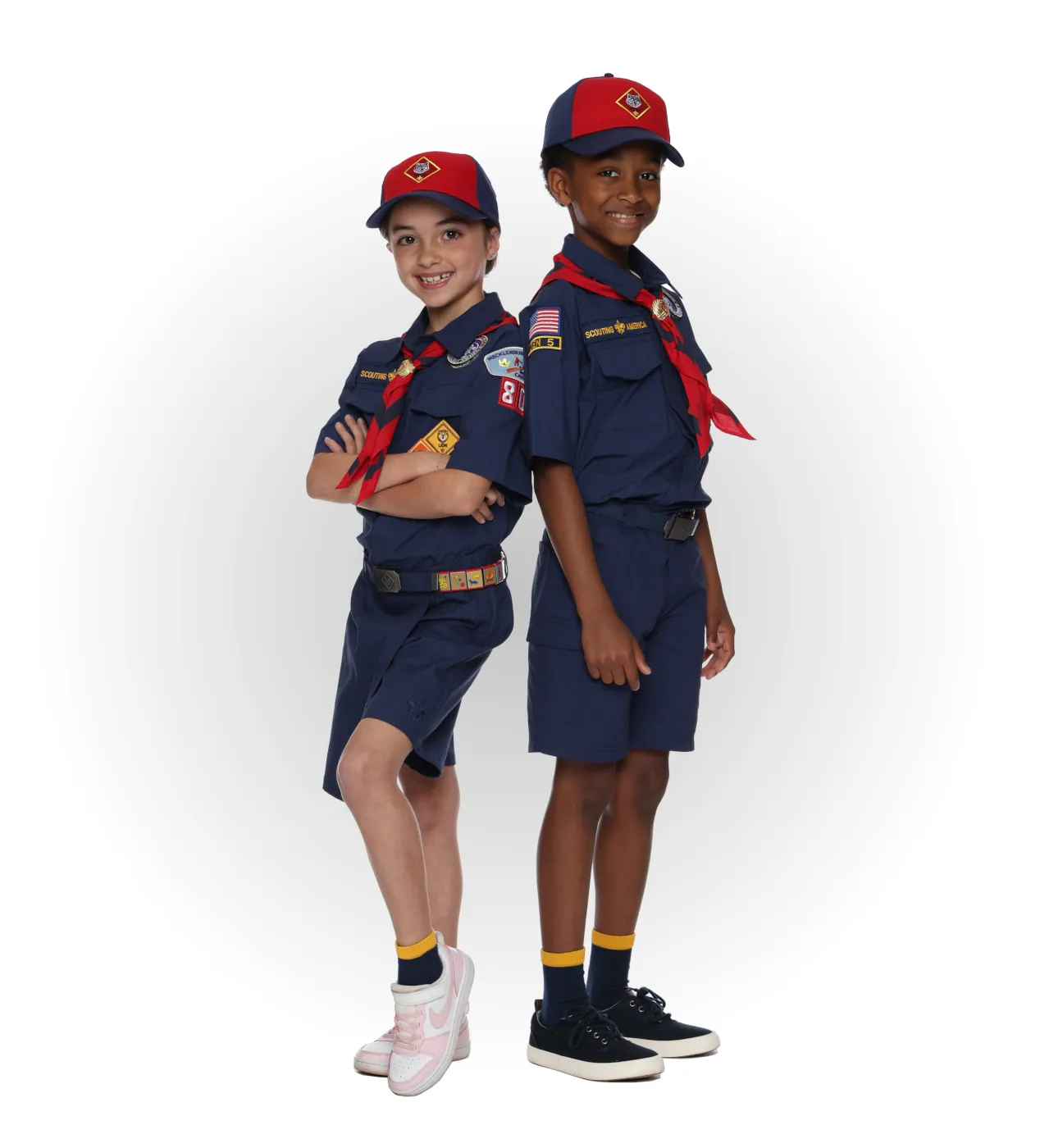 Two Wolf Cub Scouts wearing blue uniforms with red neckerchiefs and red-and-navy caps.